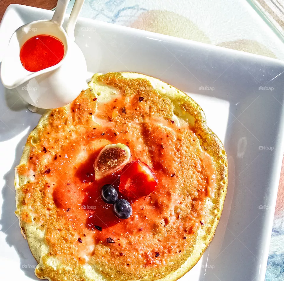 Pancakes for breakfast, served with a small jug of a fruity sauce.