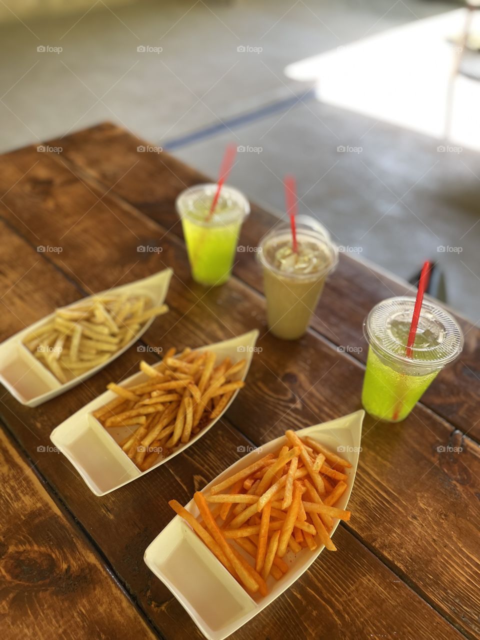 Three flavors of french fries with thirst quenching drinks.