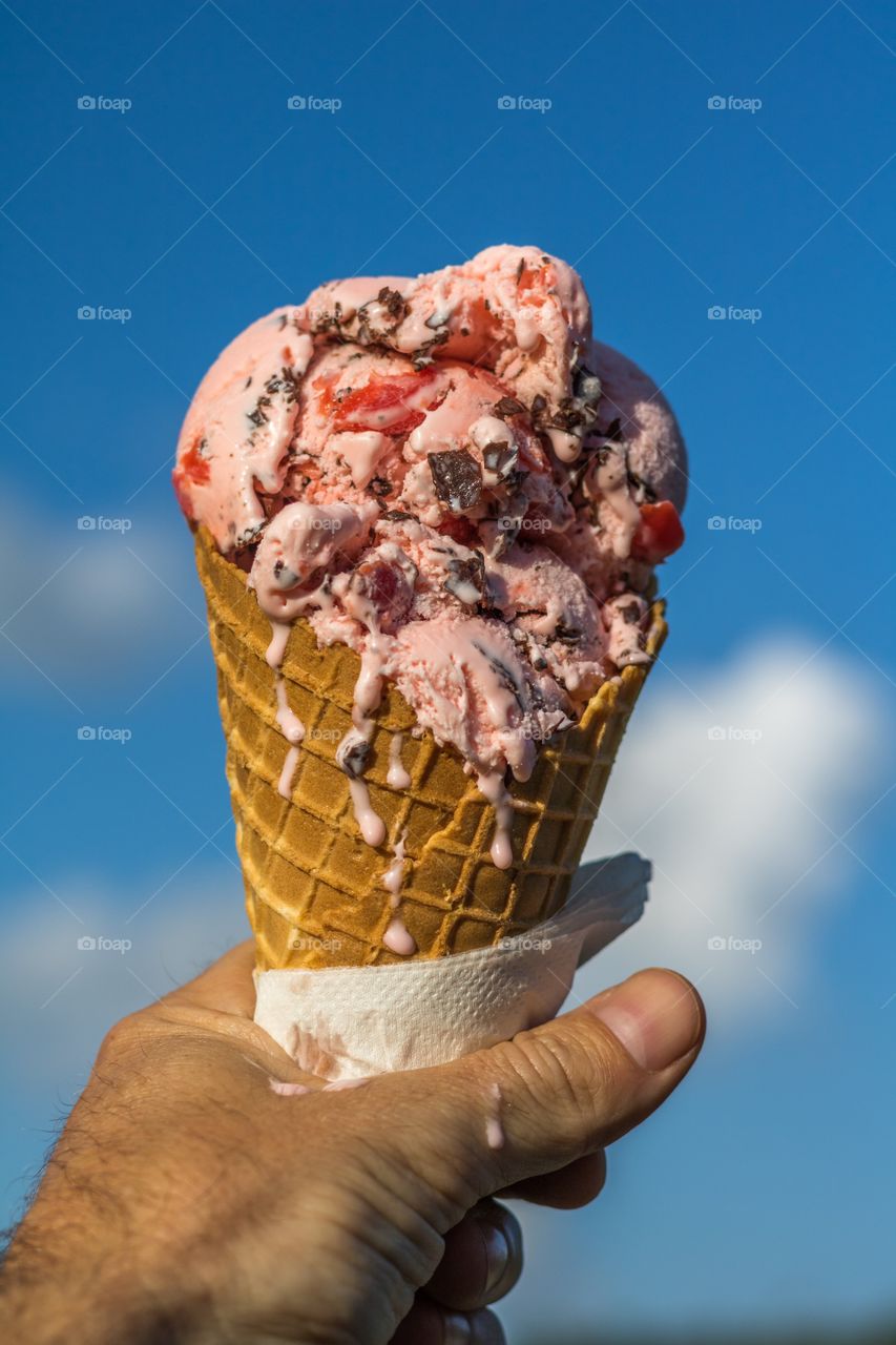 Melting cherry chocolate chip ice cream in a waffle cone