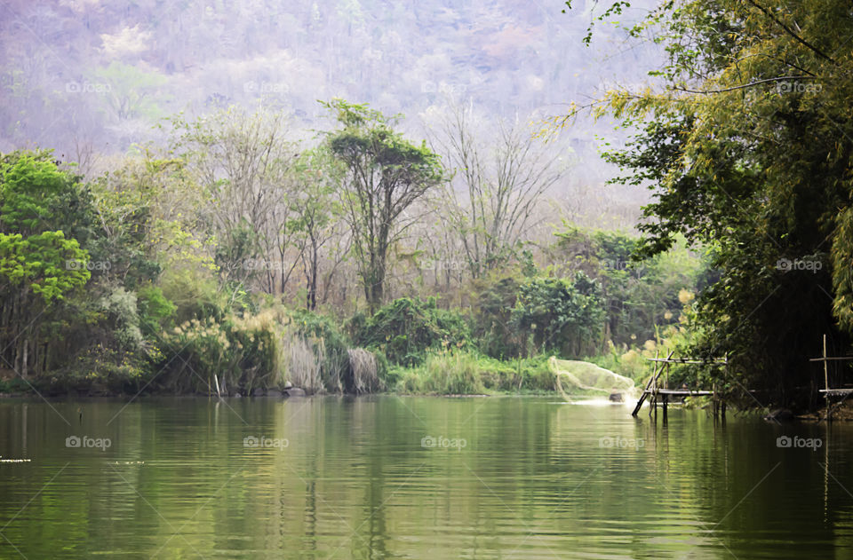 Blurry man cast fishing nets in the water Background mountains and trees.