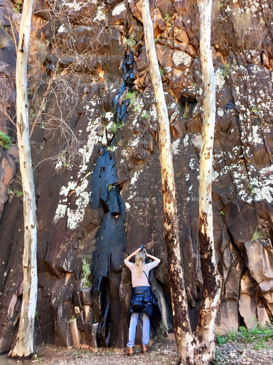 A day in the life of a Foaper! (Me!). Female photographer photographing aboriginal inscriptions markings on cliff rock wall in the Flinders Ranges of south Australia 