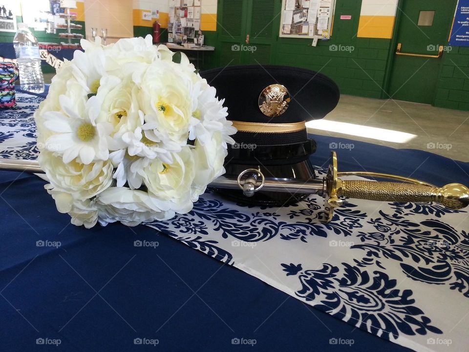 the feminine white bouquet of flowers next to the masculine Army cover & sword