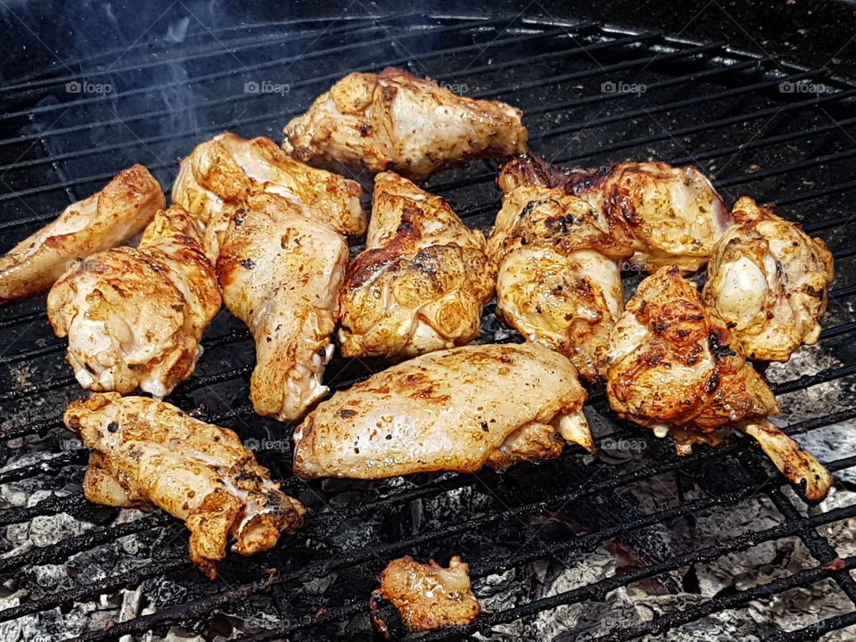 Cooking marinated chicken pieces on a BBQ