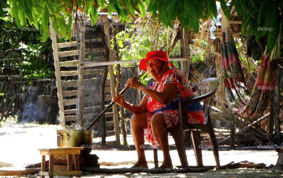 An old woman cooking. An old lady cooking outside