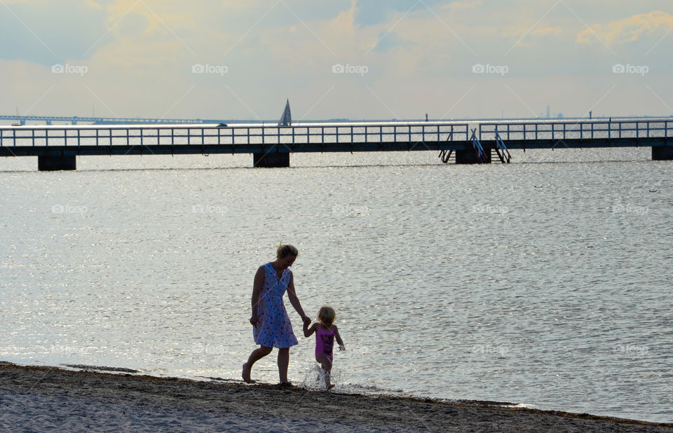 Mother and doughter walking along the beach at ribban in Malmö Sweden.