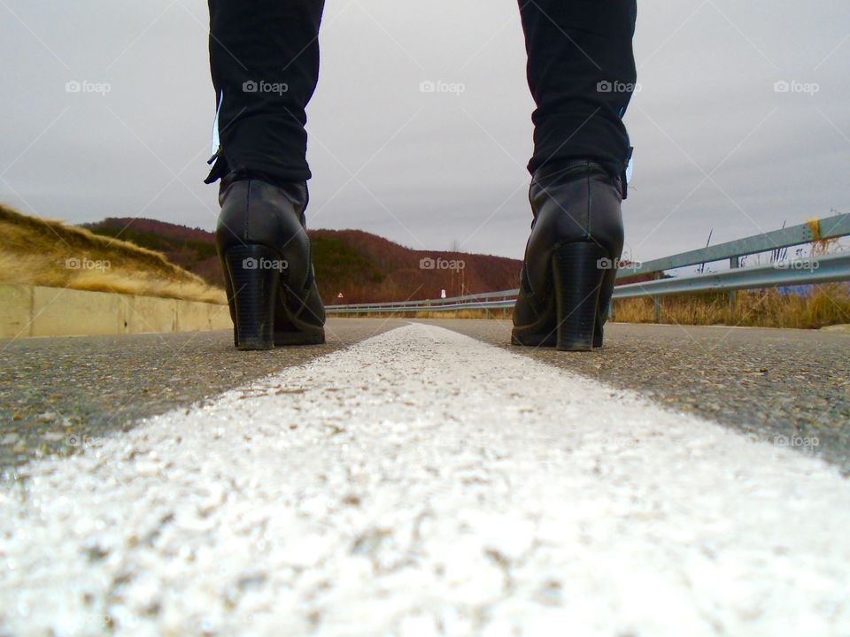 Women's black boots in the middle of the road