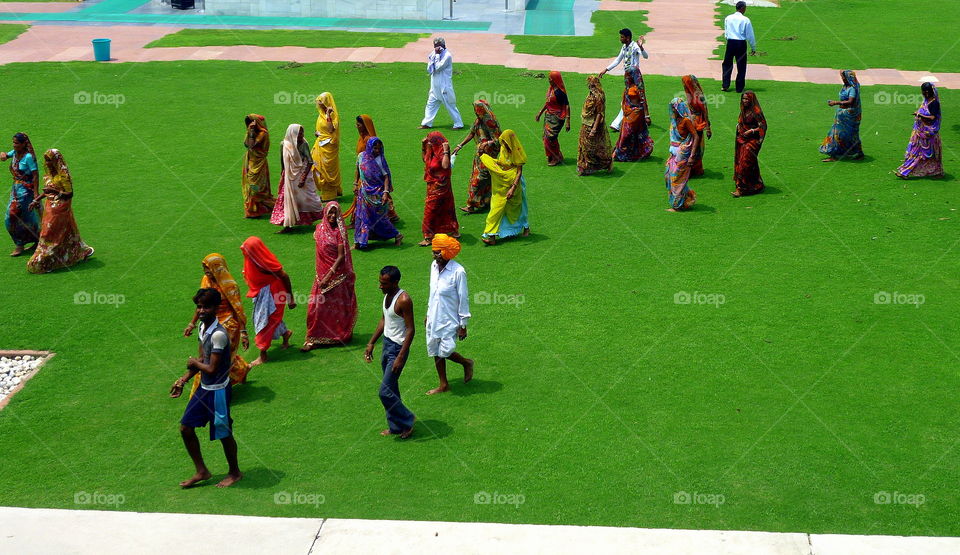 indian people wearing coloured clothes walking on a lawn