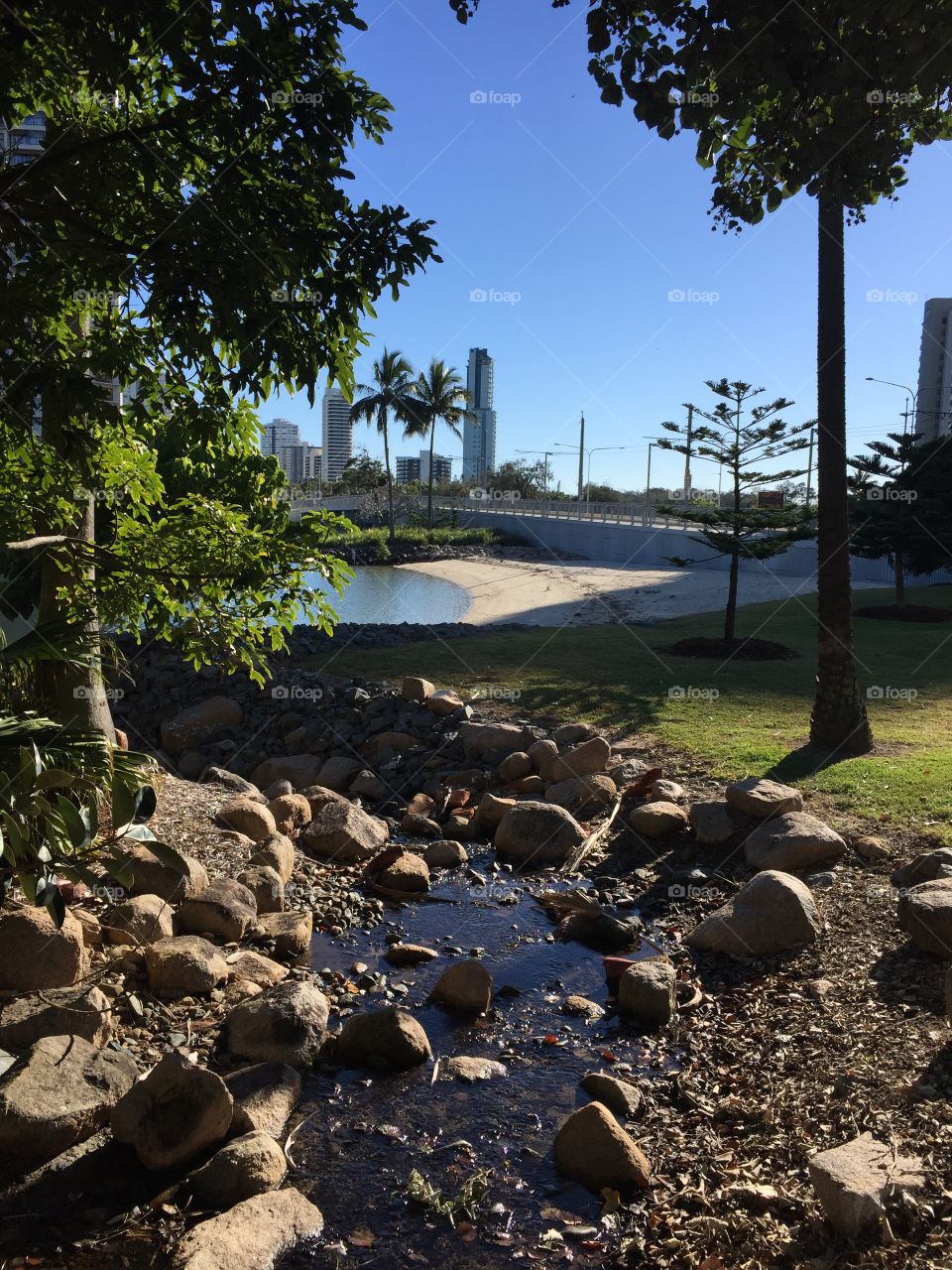 Stream leading up to a beach beneath the city Skyline in Australia 