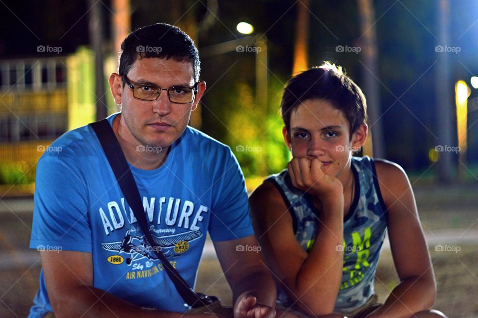 father and a son sets near in evening