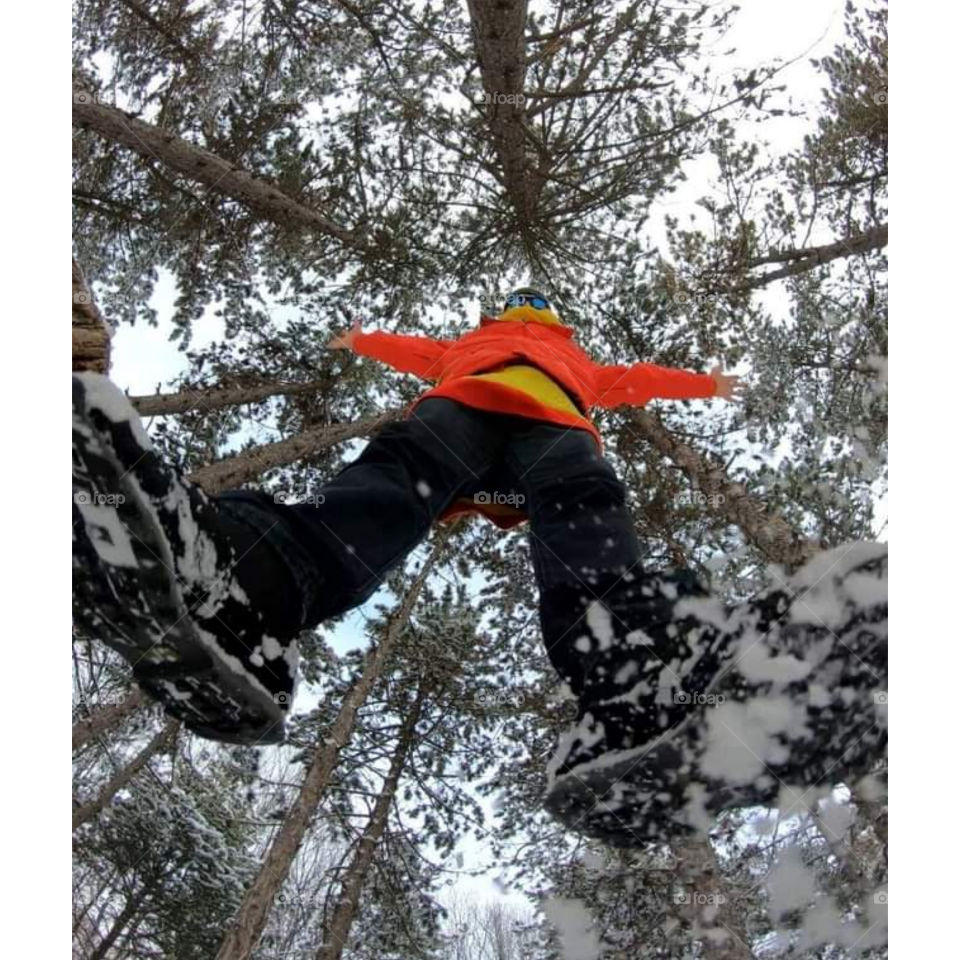 a man in a ski suit jumps in the snow photographed from below