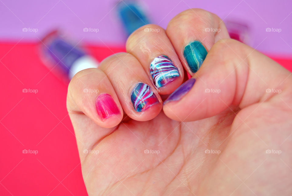 water marble nail art in purple, magenta, bluegreen and white. Nail polish blurred in background
