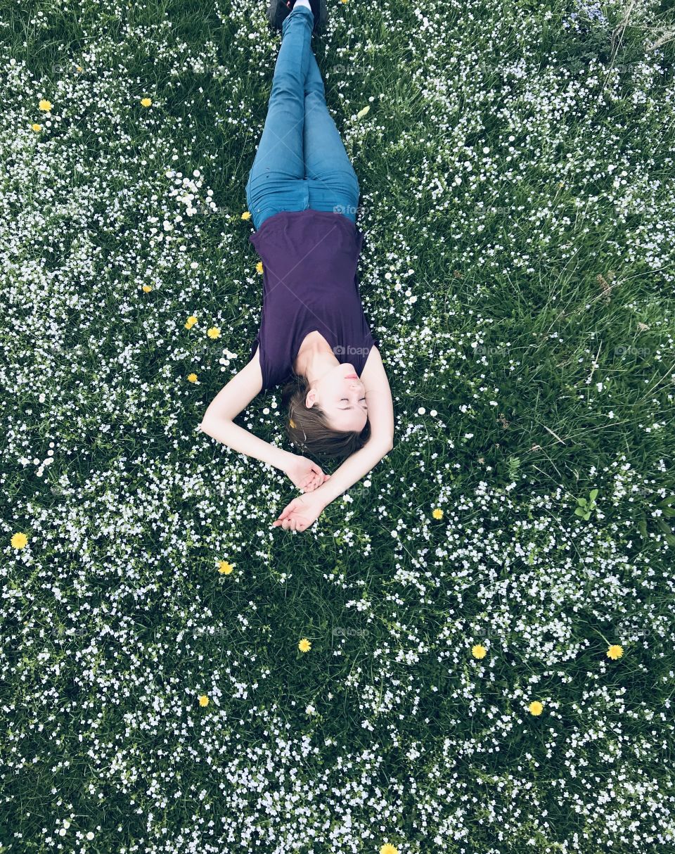 Girl laying on the grass with lot’s of flowers