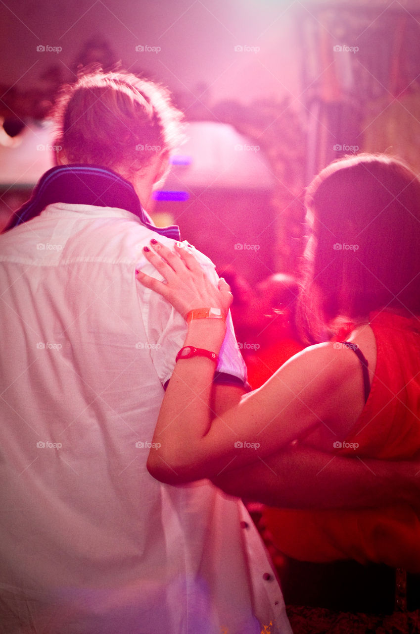 couple dancing and red lightning around. Photo taken from behind. Lady with red nails. Men in with shirt 