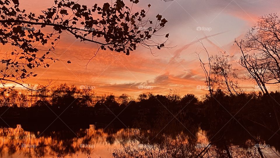 Sunset is in full bloom. Colours are moving around brighter, Softer, multiple colours, clouds glowing, Reflections off the Lake Water. 