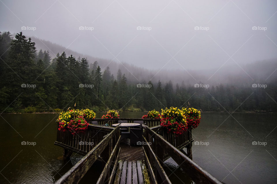 Bridge over lake decorated with flowers on a foggy day