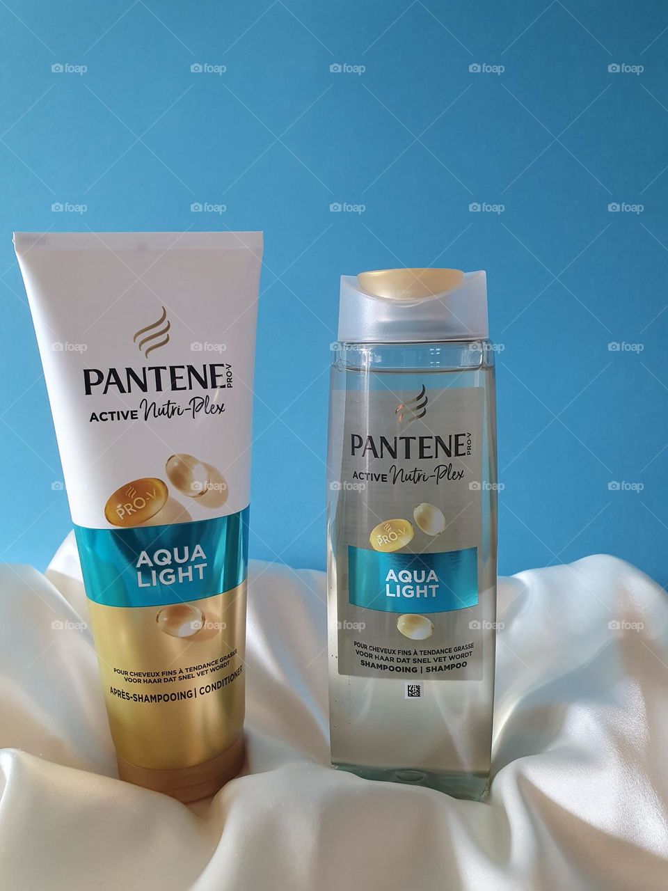 Pantene Active Nutri-Plex Aqua Light shampoo and conditioner presented on a cream satin fabric with a turquoise blue background