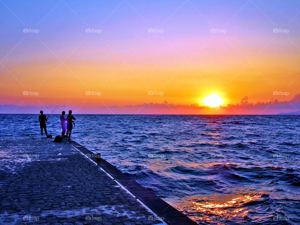 Guys are fishing  on the pier of Palinuro ( Italy ).