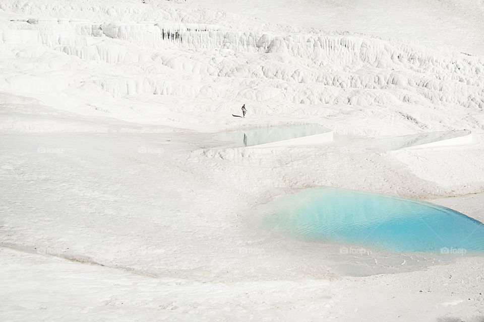 Tiny human walking at the chalk mountain with blue lagoons 