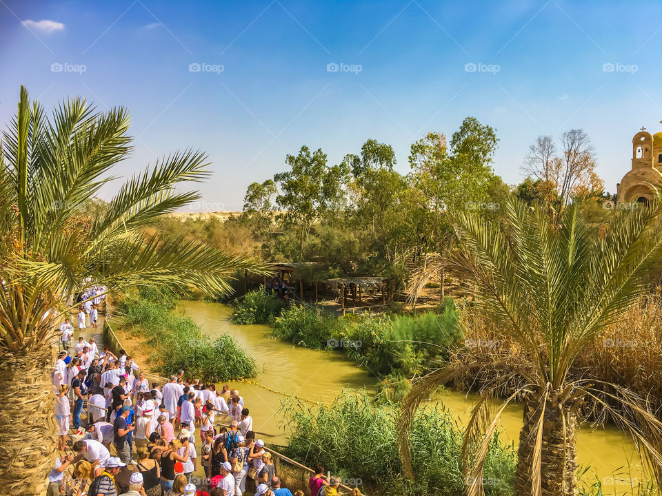 Jordan river and people waiting to be baptized