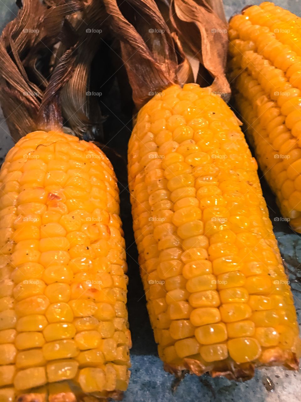 Roasted corn on the carb with husk husks close up