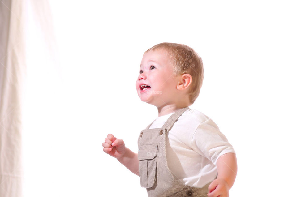 A HAPPY, SMILING YOUNG WHITE BOY LOOKS UPWARD AND TO THE LEFT AS HE IS