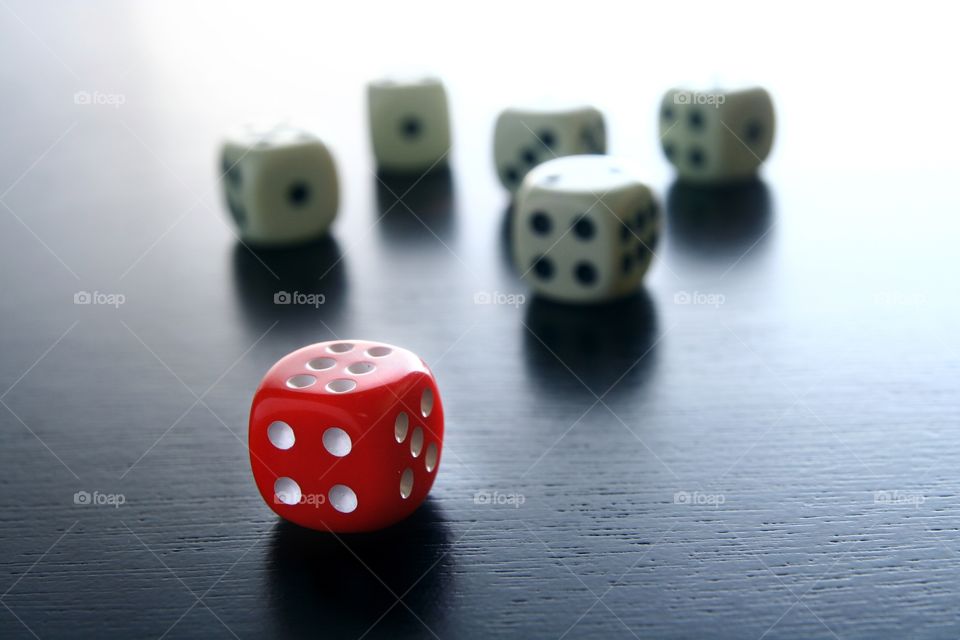 red and white game dice. 1 red game dice in front of 5 white game dice