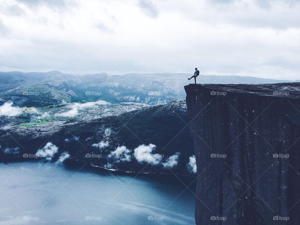 Silhouette stepping down from the edge on the Prekestolen rock in Norway. 