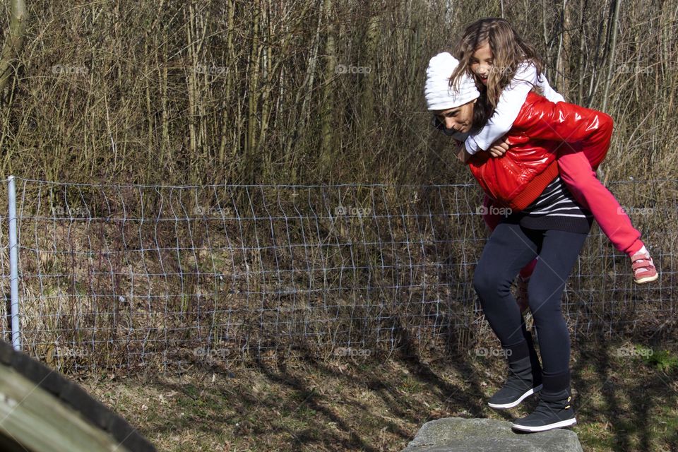 Mother Carrying Daughter On Back Smiling