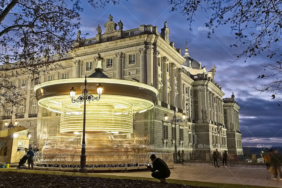 Spinning carousel in front of the illuminated royal palace in Madrid 