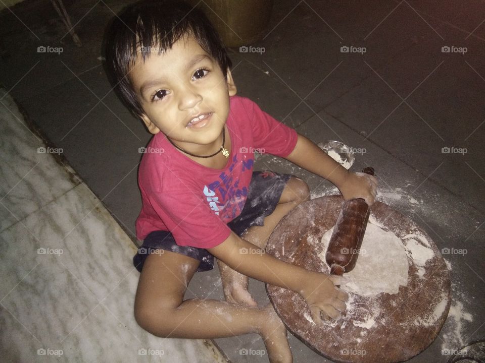 kid rolling and making dough nut chapati