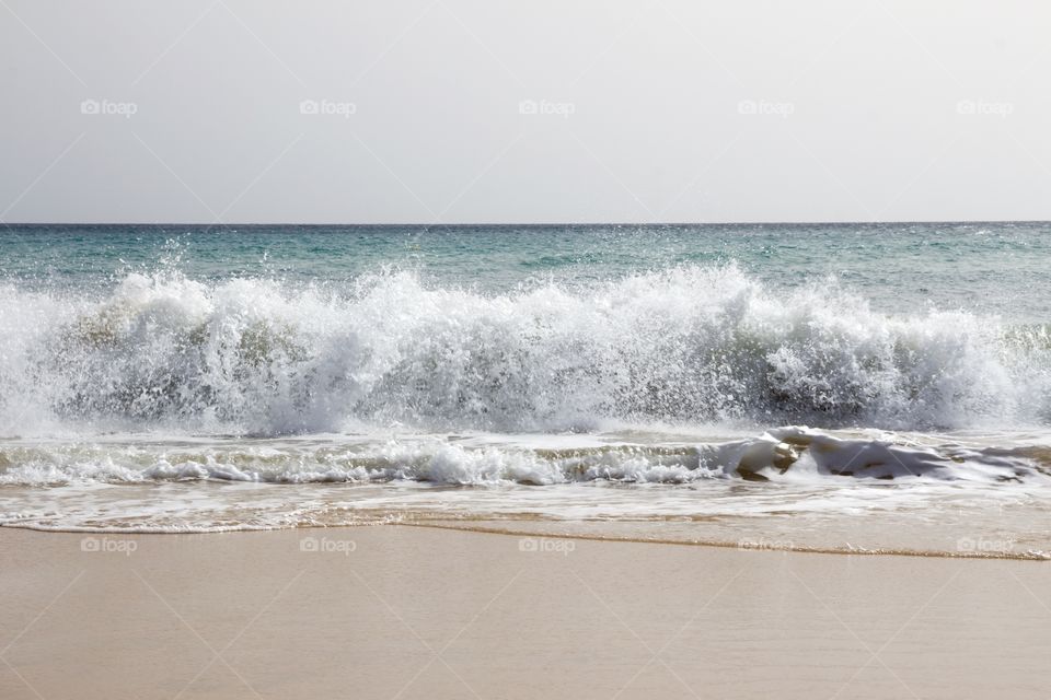 Beautiful sandy beach with waves on a sunny day on vacation in Fuerteventura, Canary Islands - fin Sandstrand med höga vågor på Kanarieöarna , semester 