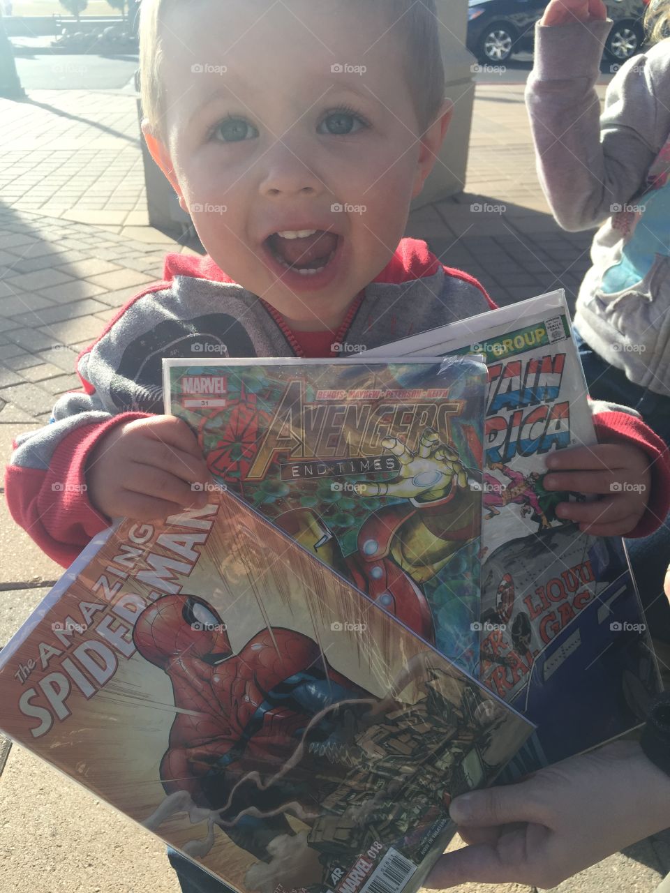 A little boy holding magazine at street