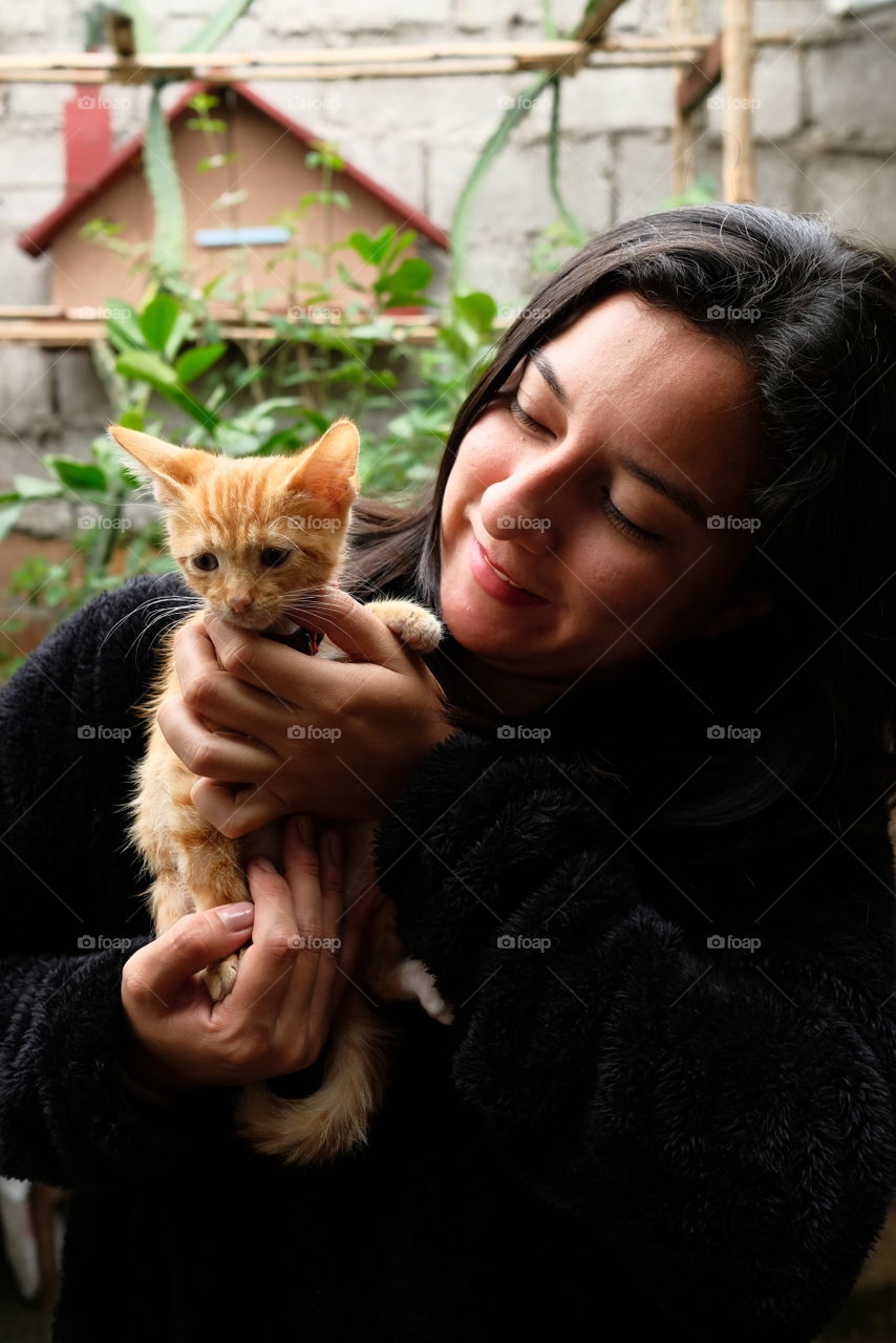 Woman with small yellow cat shows happiness at having it as a pet