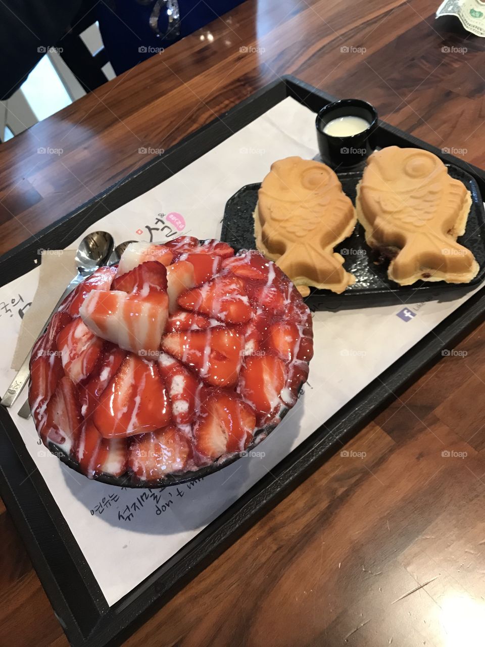Delicious Korean dessert called bingsu, made with shaved ice and usually topped with sweet toppings like these strawberries and condensed milk.