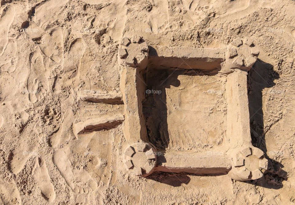 Beautiful view of the sandy medieval castle on the seashore on a summer sunny day, flat lay close-up.