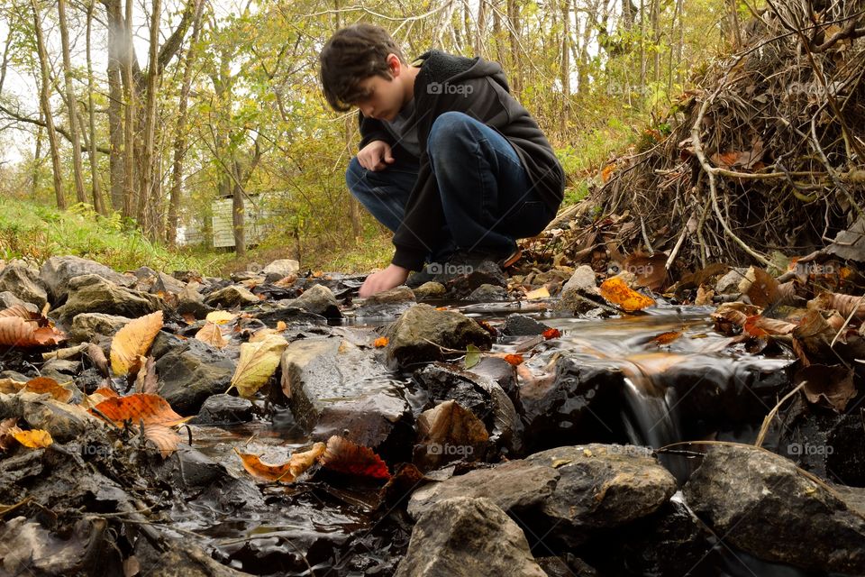 Boy sitting near stream