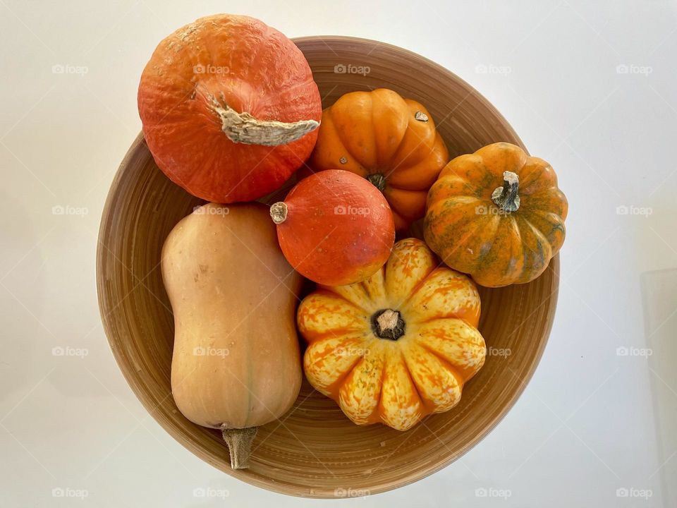 Basket containing assorted pumpkins against white background from above 