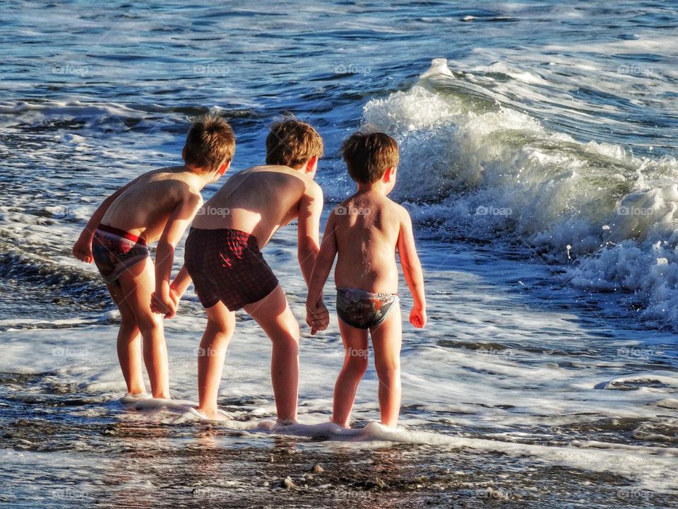 Three Little Brothers Holding Hands In The Surf. Brothers Holding Hands
