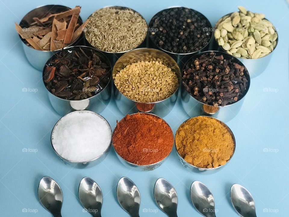 Steel cups and steel spoons with Indian spices 