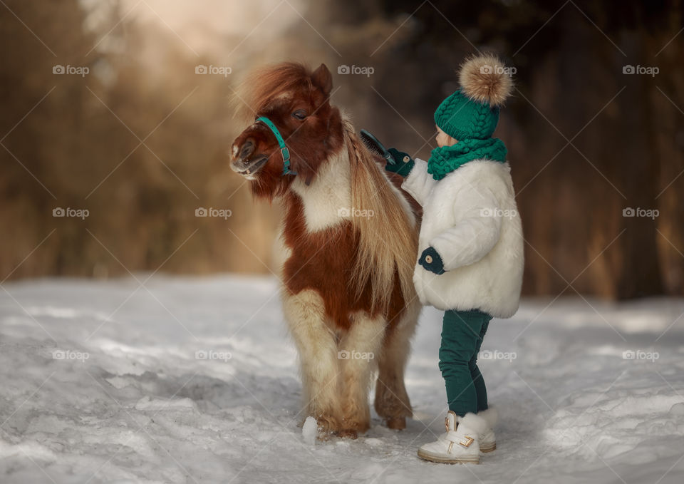 Little girl with pony at early spring day