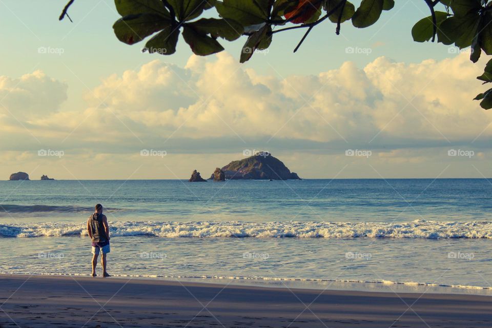 A little moments of happiness.  A young man stands on the seashore and enjoys the view