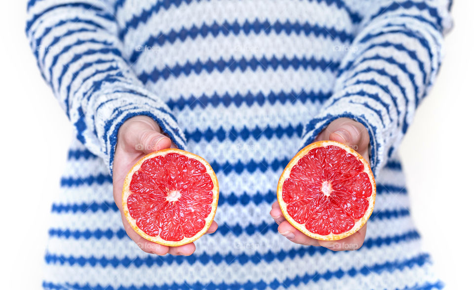 Two halfs of cut grapefruit in woman's hands