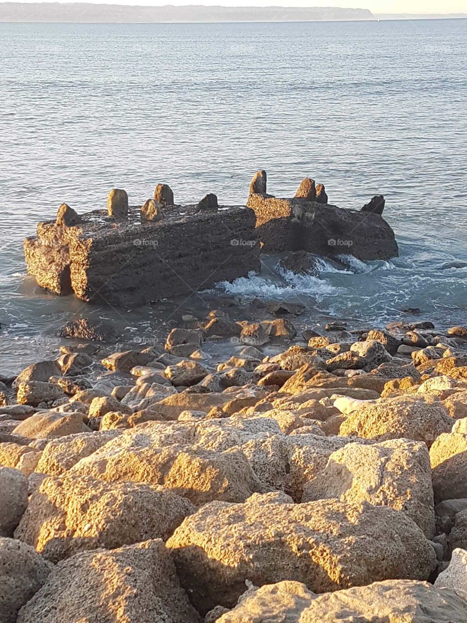 lime stone rock beach front. Remains of an old structure slowly being reduced by the sea.