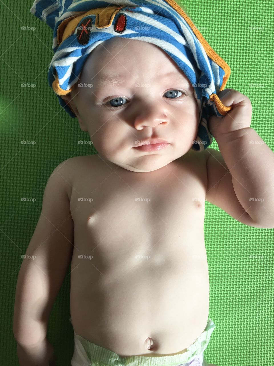 Cute baby boy not amused with clothing on head