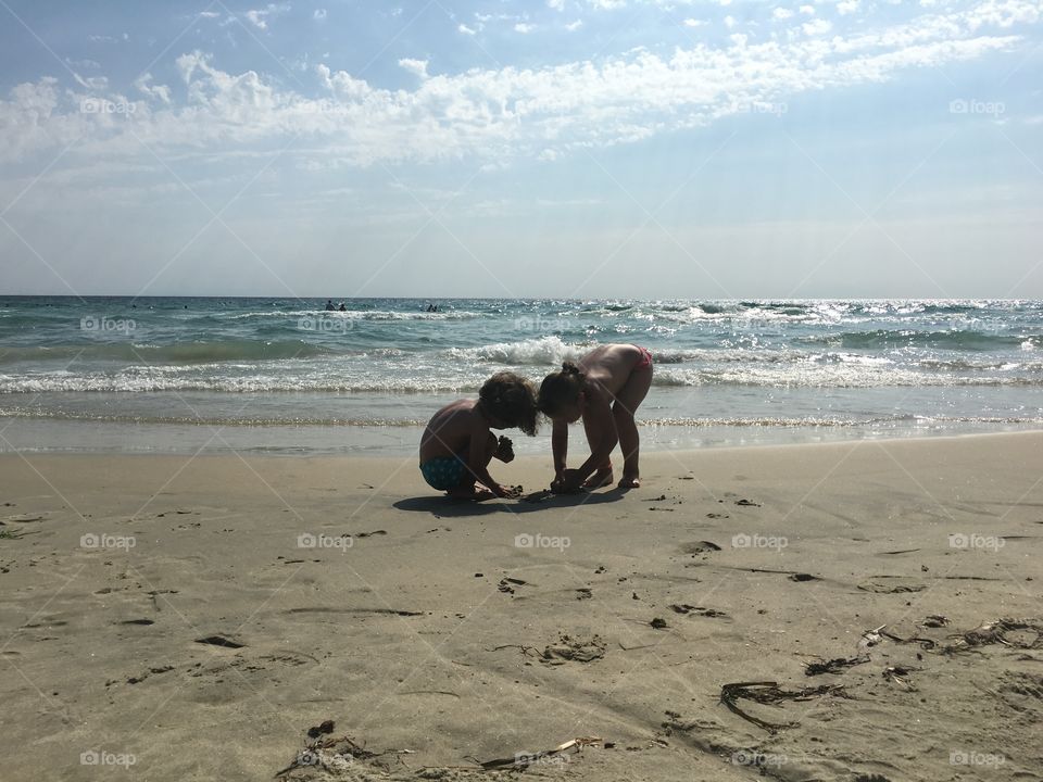 Two kids playing in sand on beach