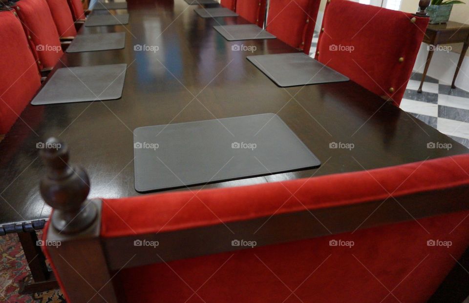 Dining table and chairs. Large wood dining table with red chairs and black placemats.