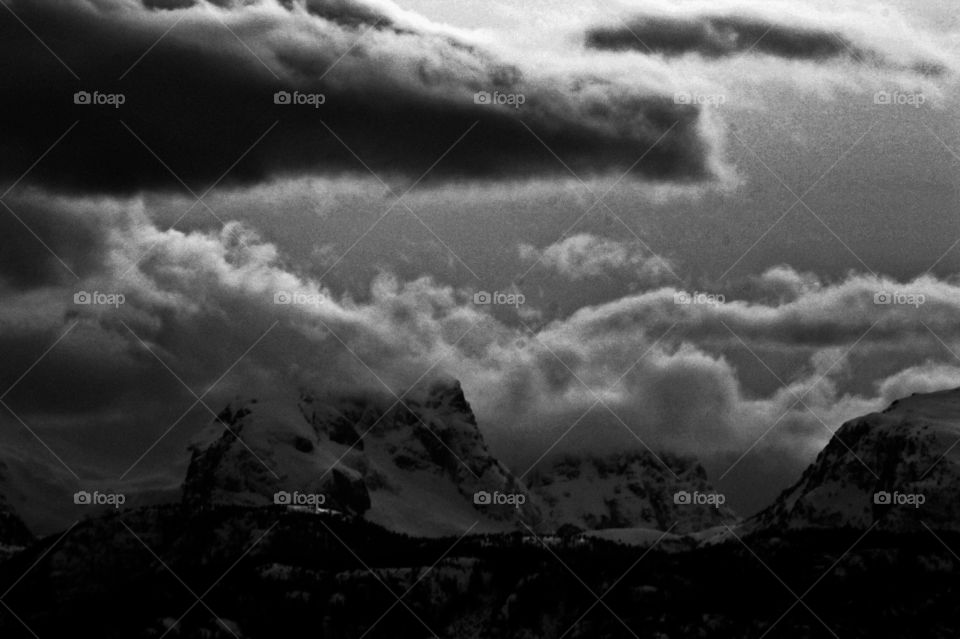 B&W. The sun shining from behind and between the stormy clouds against the snow capped mountains made beautiful contrast for a black & white photo. 