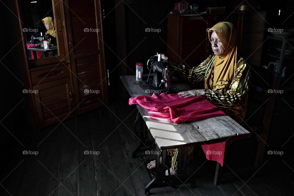 sewing in front of the window.