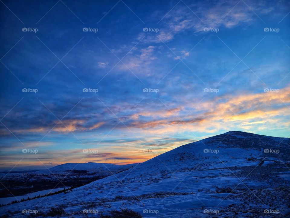 Sunrises coming up over a pyramid shaped mountain