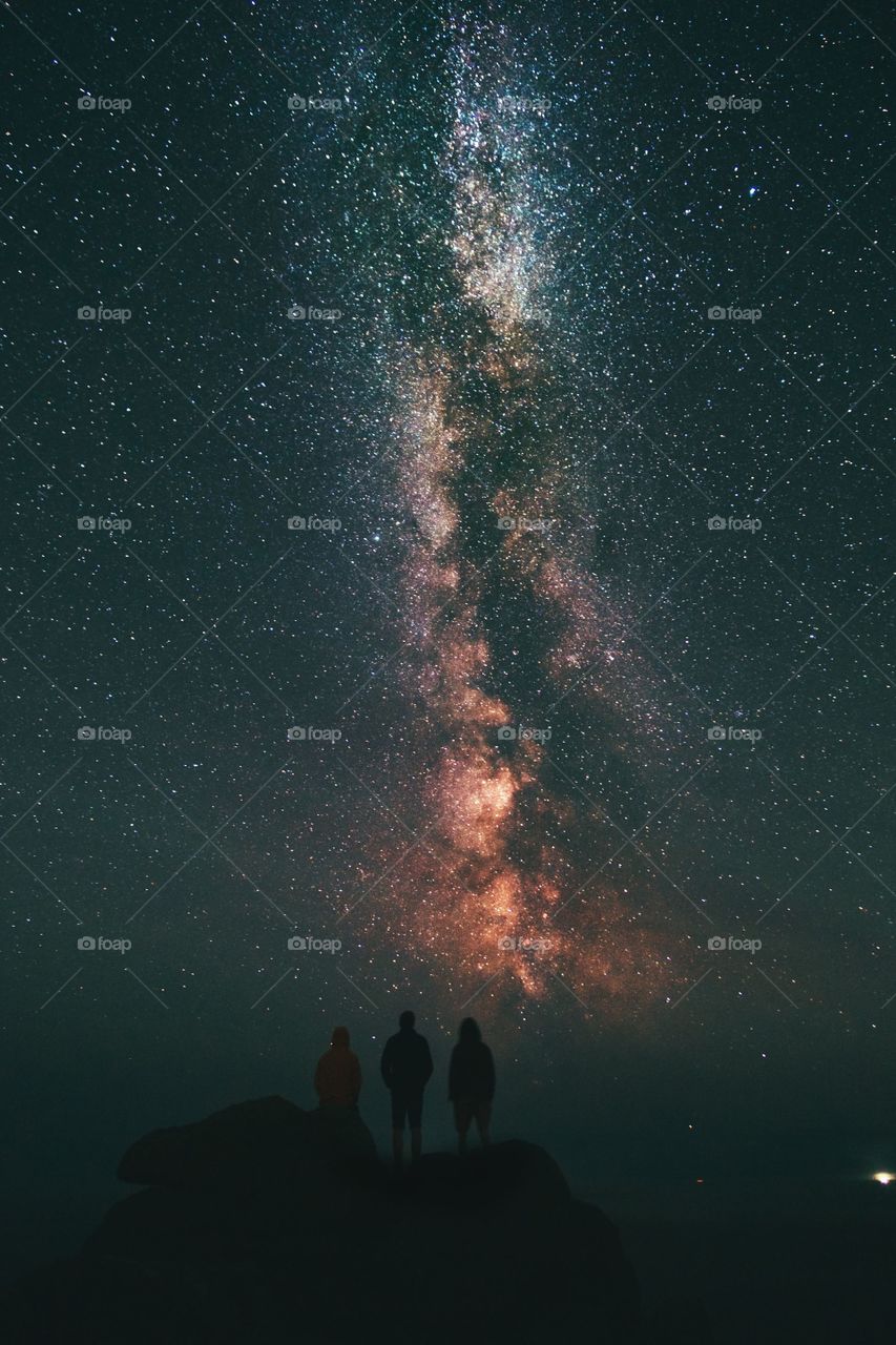 silhouette of three people starring at a vibrant starry night